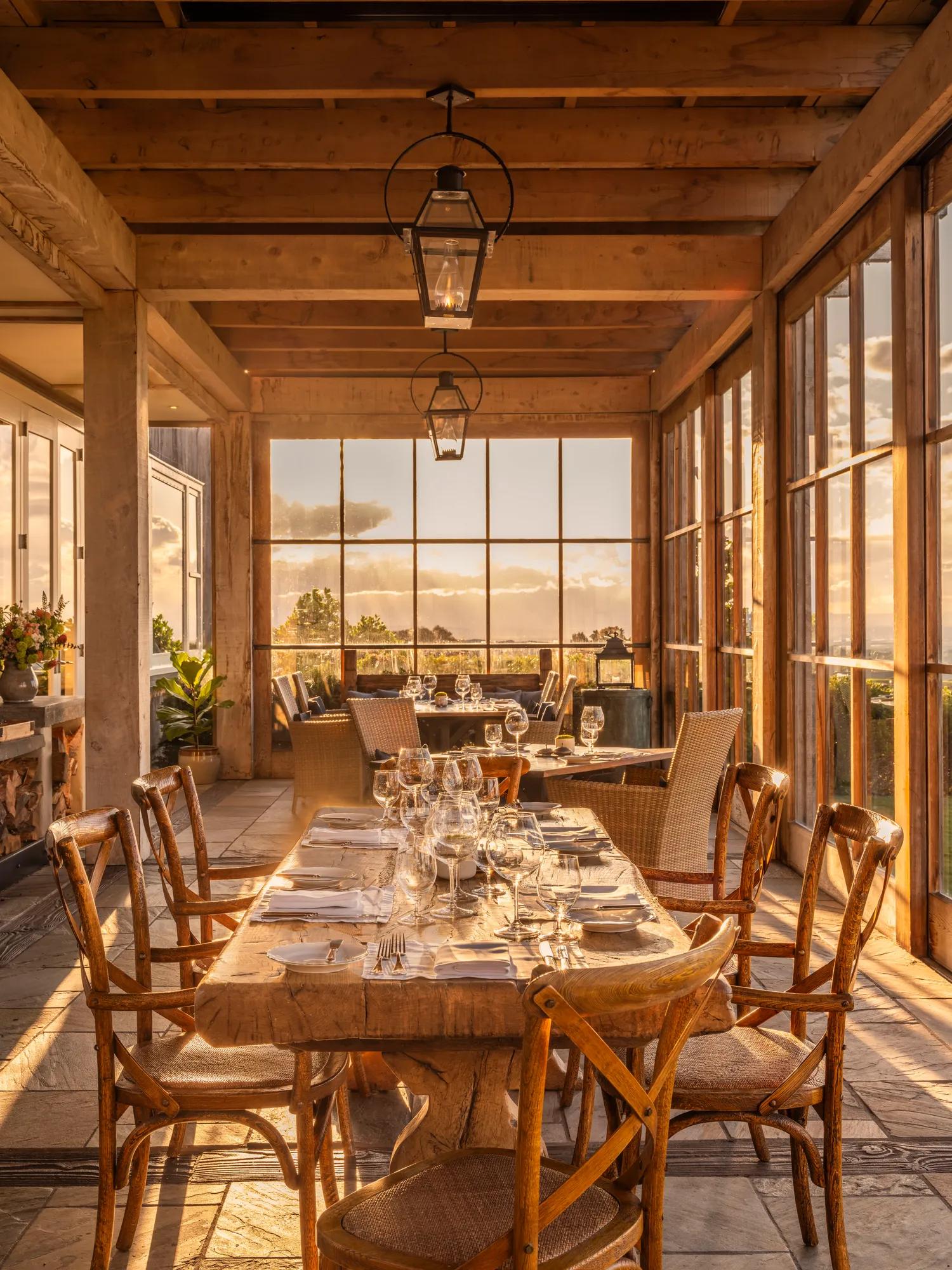 Restaurant dining room with wooden beams and floor-to-ceiling windows.