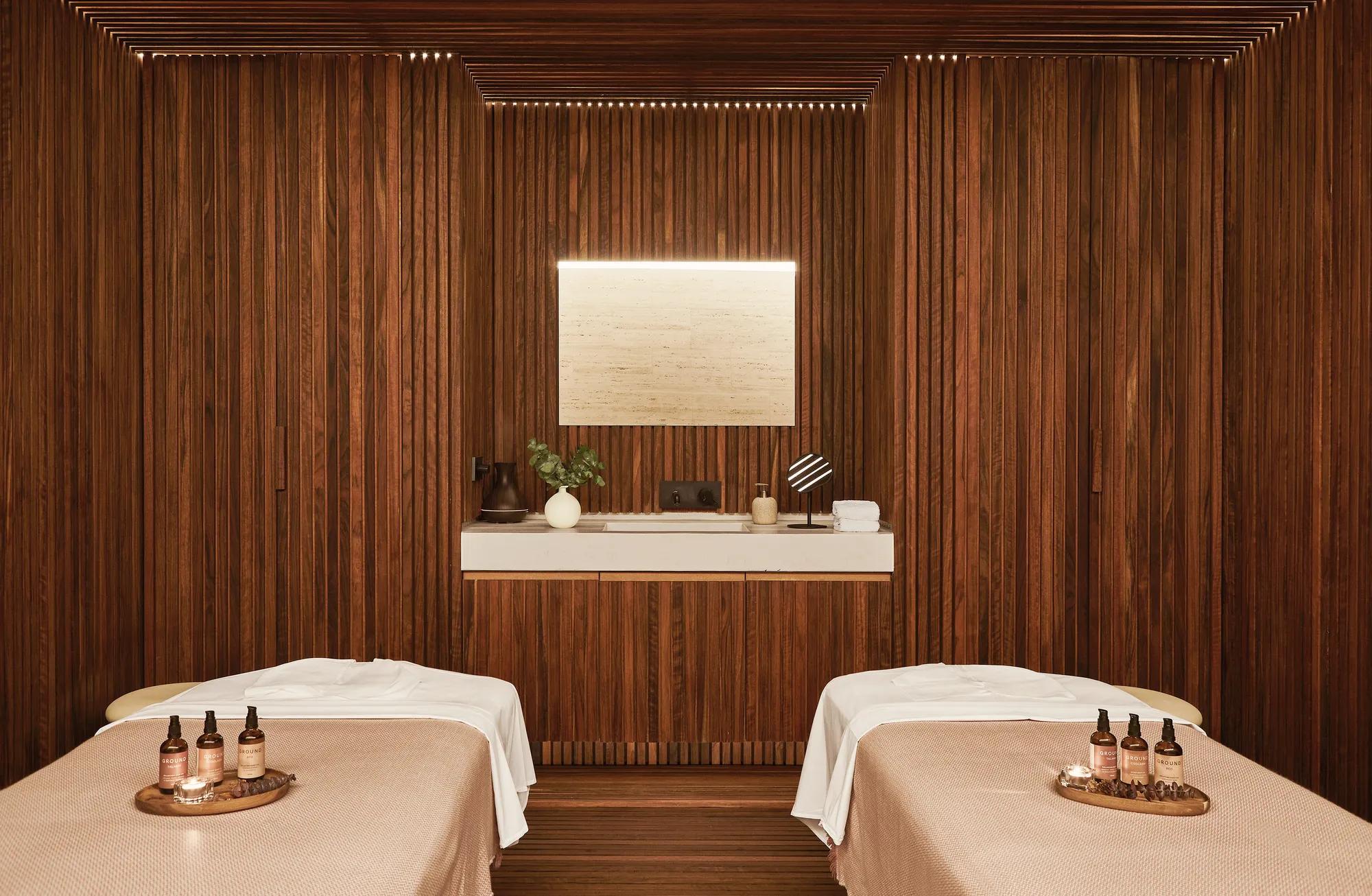 Double spa cabin featuring two treatment beds in a warmly lit room with wooden walls and elegant décor