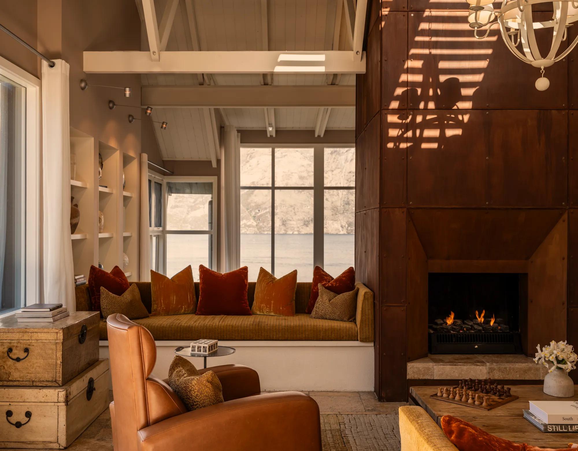 Inviting sitting area at Rosewood Matakauri with open fire with Corten steel surrounds and distant views of Lake Wakatipu.